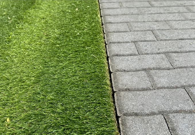 Bordure de pelouse coupée net le long d'une allée de pavés